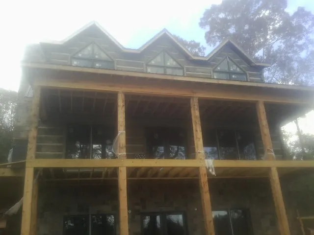 Dormers and porch framing on a large log home under construction — Roof Coating work by our crew in Harshaw