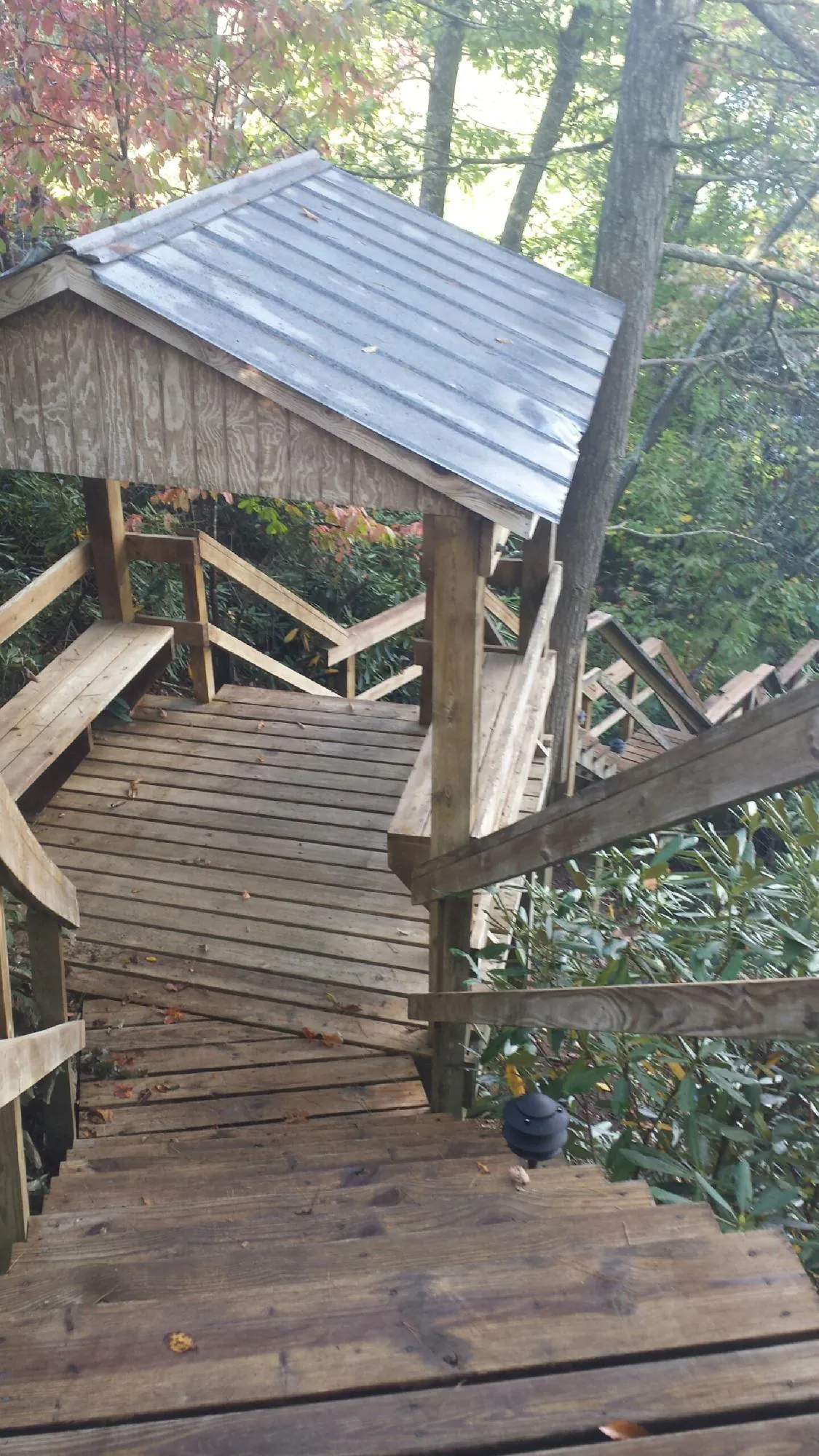 Metal roofed shelter over wooden steps on a wooded walkway — Skylight Repair & Installation work by our crew in Harshaw