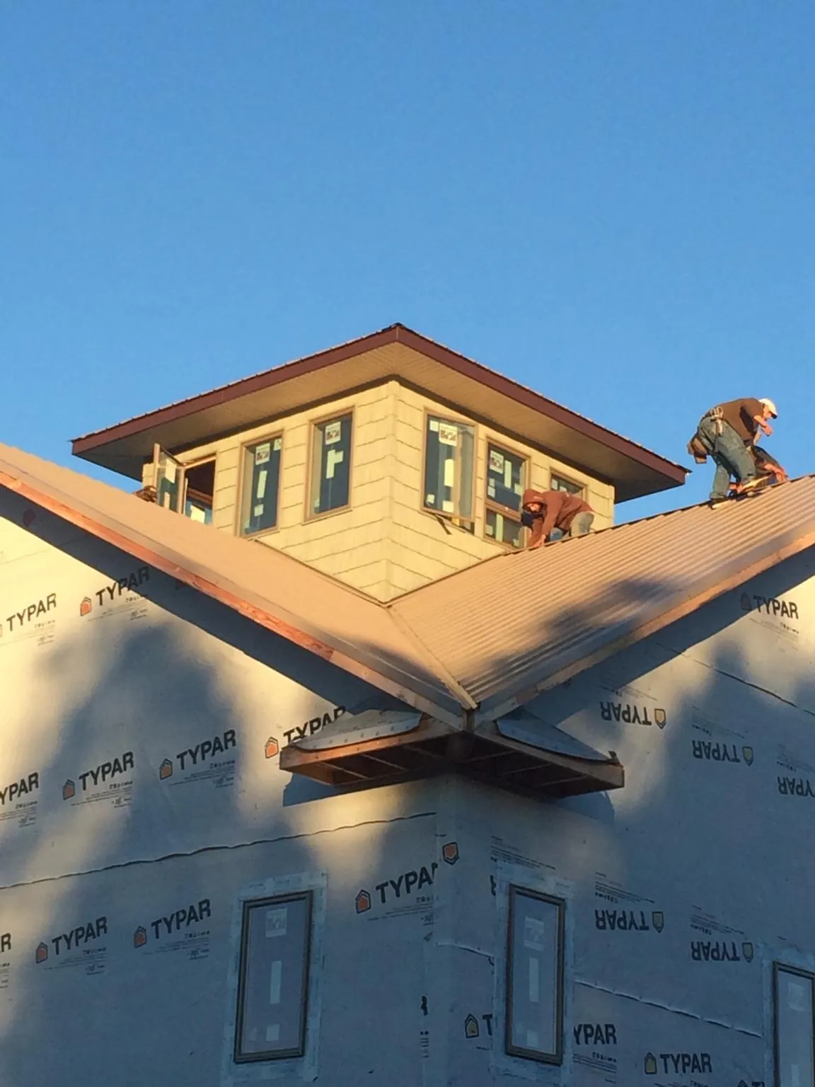 Roofers working around a rooftop cupola on a new metal roof at sunset — Roof Waterproofing in Harshaw by Roofing Brothers